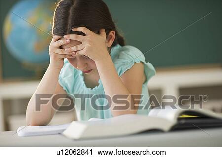 Stock Image - Schoolgirl (8-9) reading book. Fotosearch