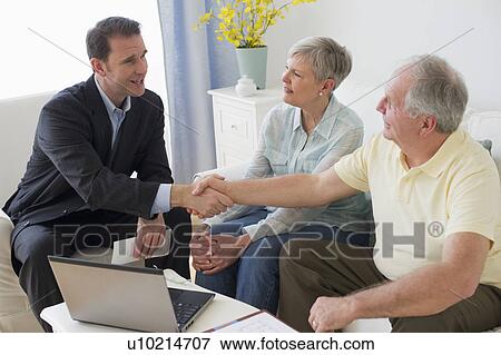 Stock Photo - Senior couple talking to businessman in living room. Fotosearch