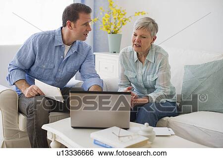 Stock Photograph - Senior mother and adult son using laptop. Fotosearch