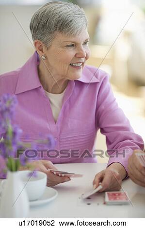 Stock Image - Senior woman playing cards. Fotosearch
