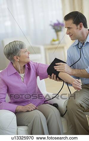 Smiling man taking senior woman's blood pressure View Large Photo Image Stock Image - Smiling man taking senior woman's blood pressure. Fotosearch