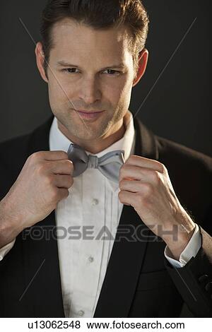 Studio portrait of bridegroom adjusting bow tie View Large Photo Image Stock Photo - Studio portrait of bridegroom adjusting bow tie. Fotosearch