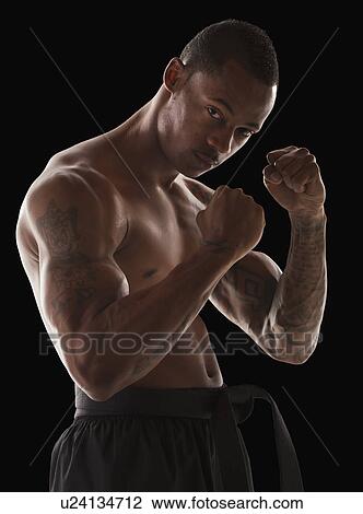 Stock Image - Studio portrait of muscular man in fighting stance. Fotosearch