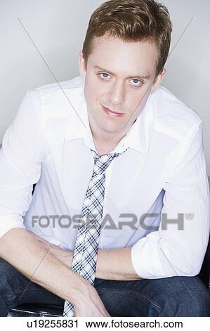 Stock Image - Studio portrait of young man smirking. Fotosearch