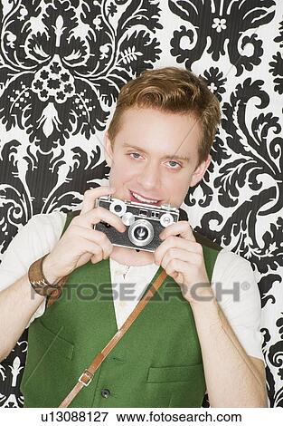 Studio portrait of young man using still camera View Large Photo Image Stock Photo - Studio portrait of young man using still camera. Fotosearch