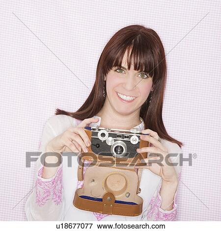 Stock Photo - Studio portrait of young woman using still camera. Fotosearch