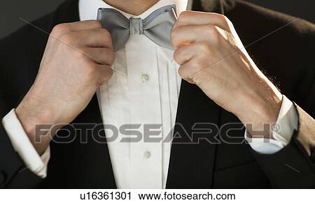 Studio shot of bridegroom adjusting bow tie View Large Photo Image Stock Image - Studio shot of bridegroom adjusting bow tie. Fotosearch