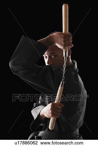 Studio shot of man exercising with nunchaku View Large Photo Image Stock Image - Studio shot of man exercising with nunchaku . Fotosearch