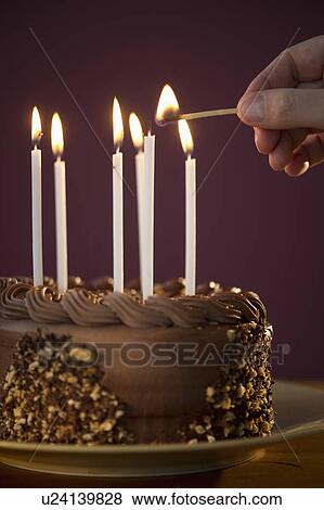 Stock Photo - Studio shot of man igniting candles on chocolate birthday cake. Fotosearch