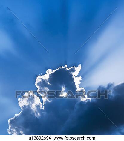 Picture - Sunbeams breaking through clouds. Fotosearch