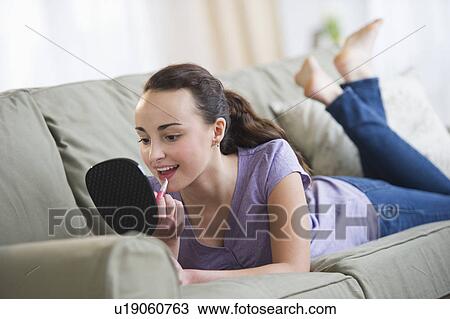 Stock Image - Teenage girl (14-15) applying lipstick. Fotosearch