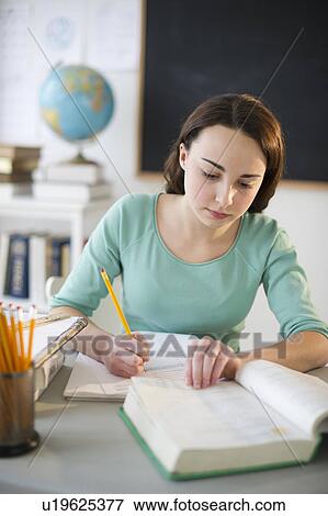 Stock Photo - Teenage girl (14-15) doing homework. Fotosearch