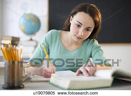 Stock Photography - Teenage girl (14-15) doing homework. Fotosearch
