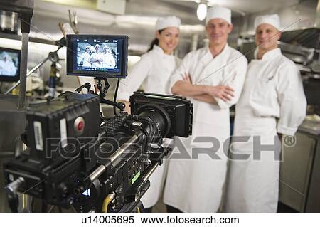 Stock Photography - Three chefs posing in kitchen, camera in foreground. Fotosearch