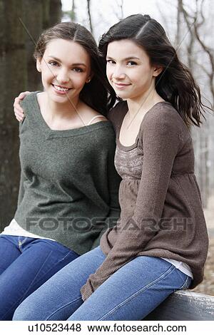 Stock Photo - Two teenage girls (16-17) sitting together, portrait. Fotosearch