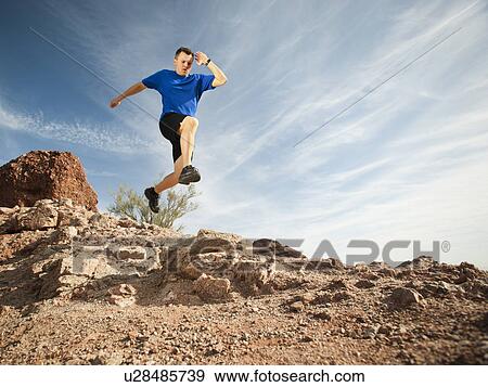 Stock Photo - USA, Arizona, Phoenix, Mid adult man jogging on desert. Fotosearch