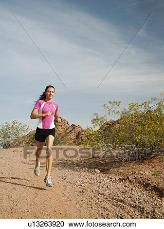 Stock Image - USA, Arizona, Phoenix, Young woman jogging on desert. Fotosearch