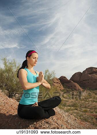 Stock Image - USA, Arizona, Phoenix, Young woman practicing yoga on desert. Fotosearch