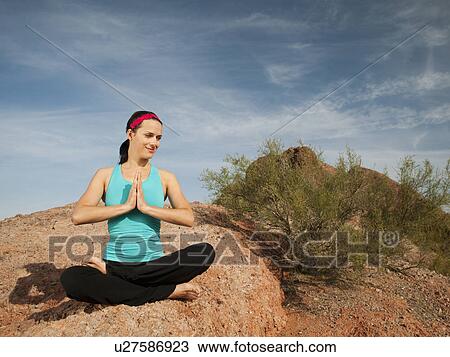 Stock Image - USA, Arizona, Phoenix, Young woman practicing yoga on desert. Fotosearch