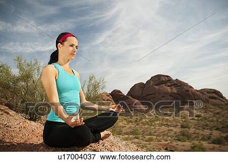 Stock Photo - USA, Arizona, Phoenix, Young woman practicing yoga on desert. Fotosearch