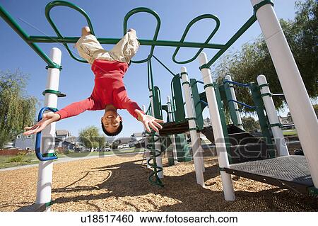 Stock Image - USA, California, Boy (12-13) climbing at playground. Fotosearch