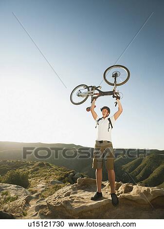 USA, California, Laguna Beach, Mountain biker on top of hill holding up his bike View Large Photo Image Stock Image - USA, California, Laguna Beach, Mountain biker on top of hill holding up his bike. Fotosearch