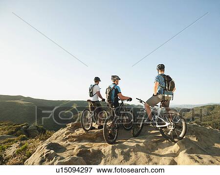 Stock Photo - USA, California, Laguna Beach, Two bikers on hill looking at view. Fotosearch