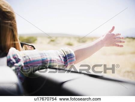 Picture - USA, California, Palm Springs, Coachella Valley, San Gorgonio Pass, Woman stretching arm outside convertible car. Fotosearch
