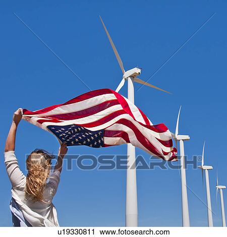 Stock Image - USA, California, Palm Springs, Woman weaving American flag with wind turbines in background. Fotosearch