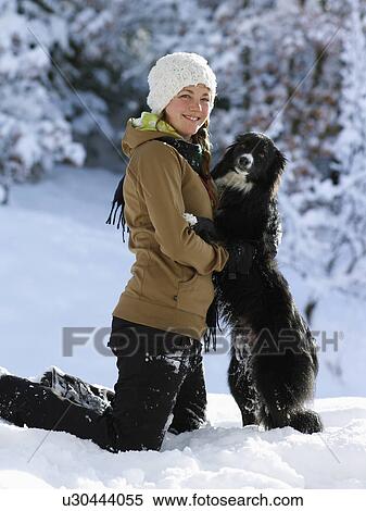 Stock Photography - USA, Colorado, portrait of young woman with dog in snow. Fotosearch