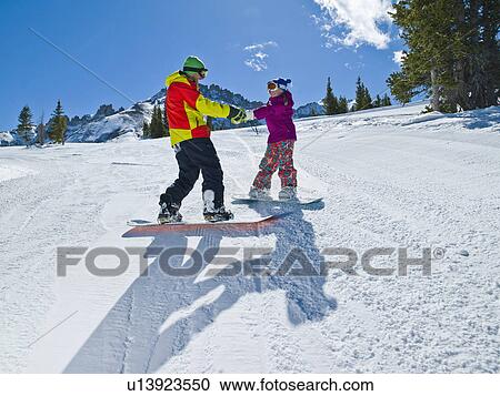 Stock Image - USA, Colorado, Telluride, Father and daughter (10-11) snowboarding . Fotosearch