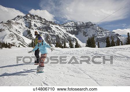 Stock Image - USA, Colorado, Telluride, Father and daughter (10-11) snowboarding . Fotosearch