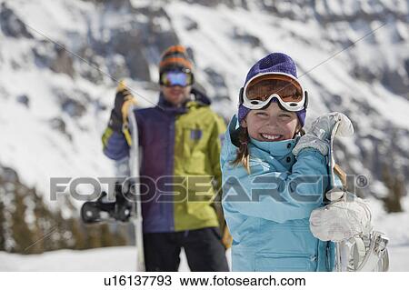 Stock Image - USA, Colorado, Telluride, Father and daughter (10-11) posing with snowboards in mountain scenery. Fotosearch