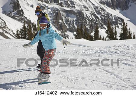 Stock Image - USA, Colorado, Telluride, Father and daughter (10-11) snowboarding . Fotosearch