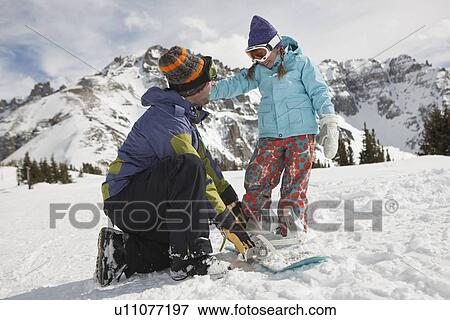 Stock Photo - USA, Colorado, Telluride, Father helping daughter (10-11) with snowboard binding. Fotosearch