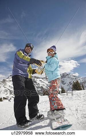 Stock Photo - USA, Colorado, Telluride, Father helping daughter (10-11) with snowboard binding. Fotosearch