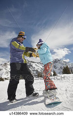 Stock Photo - USA, Colorado, Telluride, Father helping daughter (10-11) with snowboard binding. Fotosearch