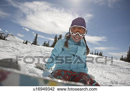 Stock Image - USA, Colorado, Telluride, Girl (10-11) posing with snowboard in winter scenery . Fotosearch
