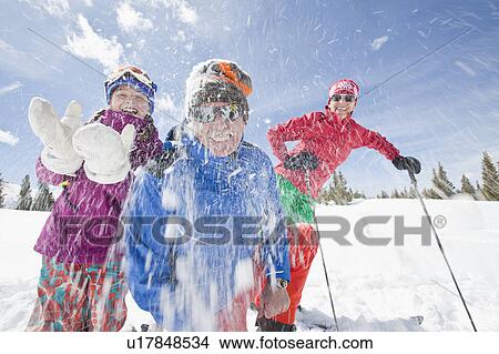 Picture - USA, Colorado, Telluride, Grandparents with girl (10-11) throwing snowballs at camera. Fotosearch