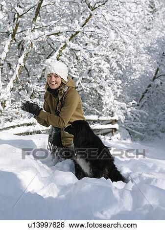 Stock Photograph - USA, Colorado, young woman playing with dog in snow. Fotosearch