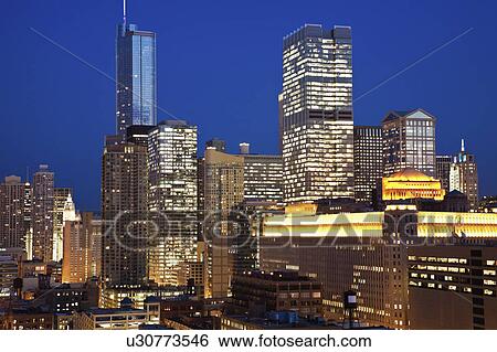 Stock Photograph - USA, Illinois, Chicago, Skyline with Merchandise Mart illuminated at night. Fotosearch