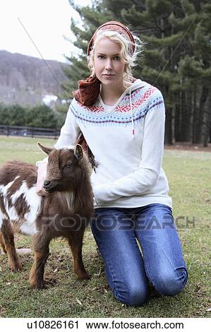 Stock Image - USA, New Jersey, Califon, Young woman at farm with young goat. Fotosearch