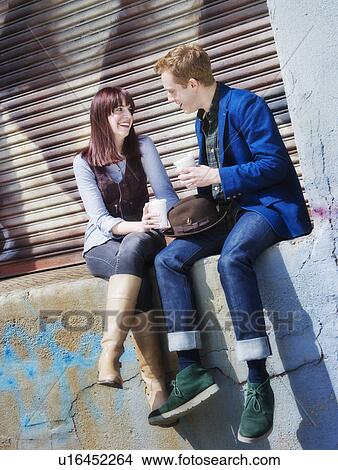 USA, New Jersey, Jersey City, young couple sitting on wall View Large Photo Image Picture - USA, New Jersey, Jersey City, young couple sitting on wall. Fotosearch