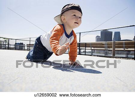 Stock Image - USA, New York City, Brooklyn, baby boy (0-1 years) crawling on sidewalk. Fotosearch
