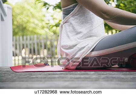 Stock Photo - USA, New York State, Long Island, woman sitting in yoga position in garden. Fotosearch