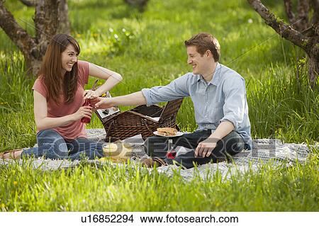 Picture - USA, Utah, Provo, Young couple having picnic in orchard. Fotosearch