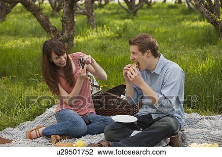 Stock Image - USA, Utah, Provo, Young couple having picnic in orchard. Fotosearch