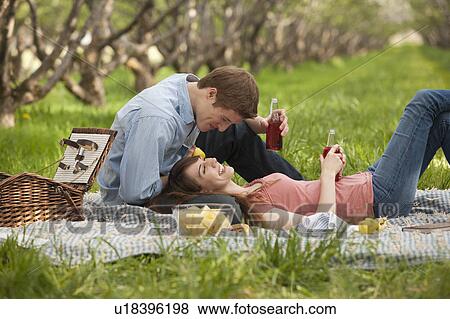 Stock Photo - USA, Utah, Provo, Young couple having picnic in orchard. Fotosearch