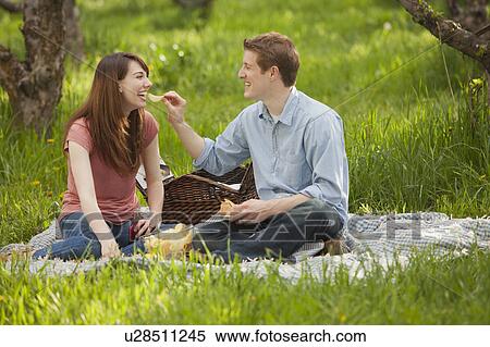 Stock Photography - USA, Utah, Provo, Young couple having picnic in orchard. Fotosearch