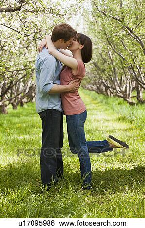 Stock Photograph - USA, Utah, Provo, Young couple kissing in orchard. Fotosearch